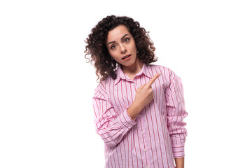 young cute curly-haired caucasian woman dressed in a striped pink blouse actively gesticulates with...