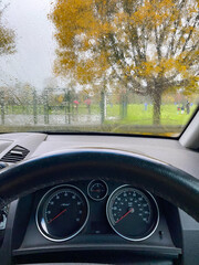 Sat in the driver's seat of a parked car, looking out through a rain covered windscreen