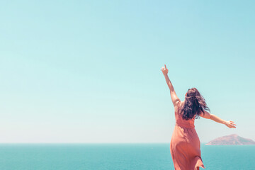 Young girl in dress looking at turquoise seascape and enjoying summer vacation