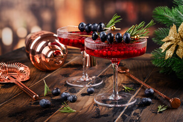 Christmas cocktail with cranberry, rosemary and blueberry over new year festive background. Copy space