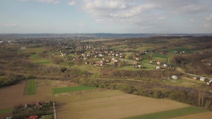 Fototapeta na wymiar Panorama from a bird's eye view. Central Europe: The Polish village is located among the green hills. Temperate climate. Flight drones or quadrocopter. Urbanization of the landscape