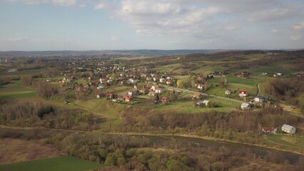 Fototapeta na wymiar Panorama from a bird's eye view. Central Europe: The Polish village is located among the green hills. Temperate climate. Flight drones or quadrocopter. Urbanization of the landscape