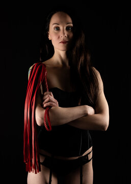 Sexy girl in black
om karset in the image of the Mistress. Holding a red leather flogger in his hands. Photographed against a dark background in low key.