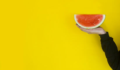 Hand holding watermelon isolated on yellow backgorund