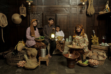 Portrait of Indonesian family wearing traditional clothes and sitting in the kitchen with happy...