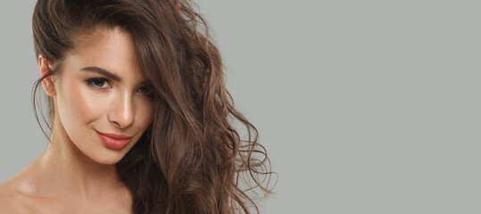 Smiling woman brunette with long dark healthy wavy hair and makeup  on gray background. Beautiful...