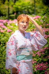 Portrait of a young woman wearing a Japanese yukata summer kimono in a hydrangea garden. Kyoto, Japan. soft blur background.