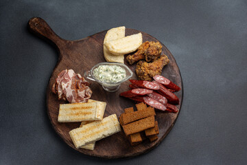 Sausage, bacon, chicken wings on a board
