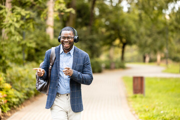 Fototapeta premium Happy man with headphones listening to music, singing and dancing while walking.