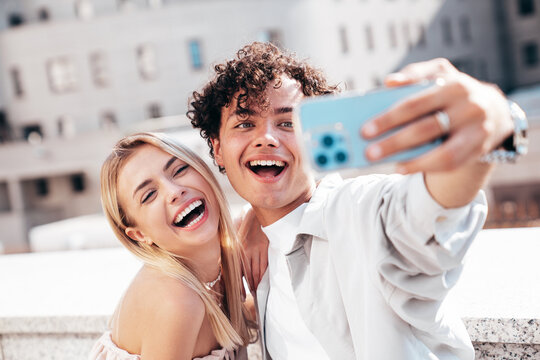 Young smiling beautiful woman and her handsome boyfriend in casual summer clothes. Happy cheerful family. Female having fun. Couple posing in the street background at sunny day. Take selfie photos