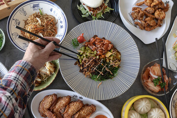 Hand holding chopsticks for eating at restaurant table