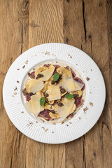 Veal carpaccio with Parmesan on a wooden table