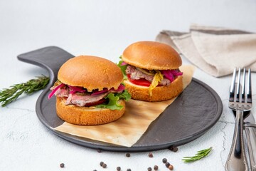 hot burgers with lettuce and vegetables on a wooden board side view