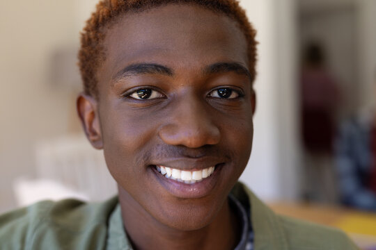 Portrait of happy african american male teenager at table at home