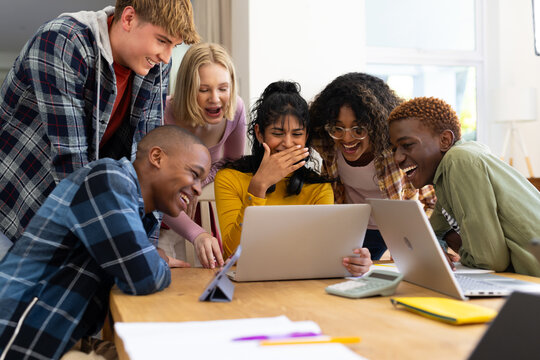 Happy Diverse Group Of Teenage Friends Studying With Laptop And Tablets At Table At Home