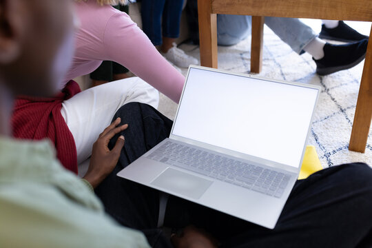 Diverse group of teenage friends studying with laptop with copy space at home