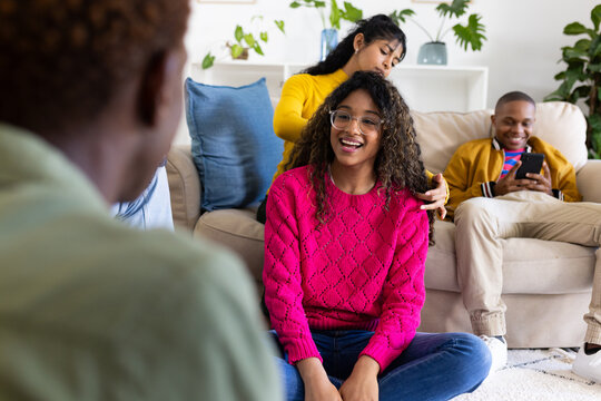 Happy diverse teenage friends using smartphone and talking in circle at home