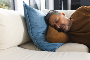 Senior biracial man lying on couch and sleeping at home