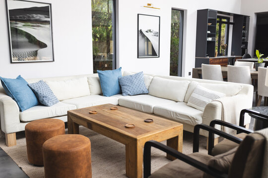 Big empty living room with wooden table, big white couch and pictures hanging on walls