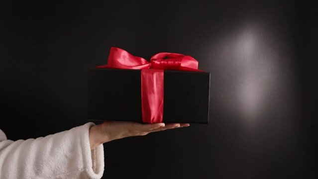 luxury gift, Hand with a black present box, Valentine's surprise, ribbon wrap, romantic event