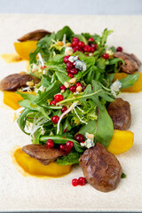 meat medallions with arugula, peach slices and red berries, side view