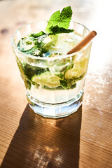 Verre de Mojito avec paille sur table en bois et soleil d'été