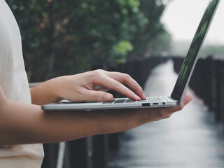 Young woman's hands holding a laptop and typing Working outside