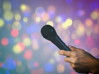 Hands up microphone on party background, blurred bokeh lights