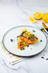 red fish with vegetable sauce and puree on a round plate side view