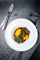 mashed potatoes with meat, sauce and herbs in a deep plate top view