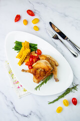 chicken thighs with corn, cherry tomatoes and herbs top view