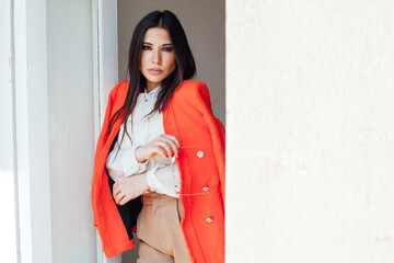 a beautiful woman in a bright jacket by the door in a bright room