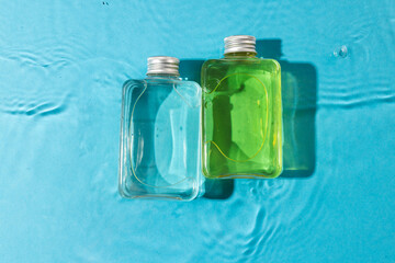 Beauty product bottles in water with copy space background on blue background