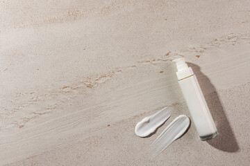 Beauty product bottle with pump and cream smudges with copy space on stone background