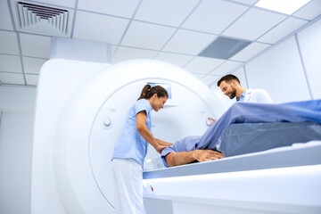 Doctors preparing patient for full body scanning procedure inside MRI diagnostic center.