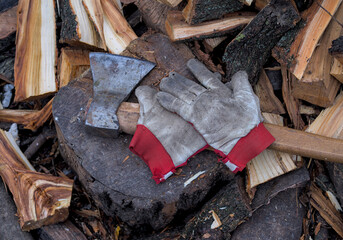 Worn leather gloves, ax and firewood