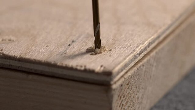 Carpenter drills plywood together with a board with a thin drill, close-up.