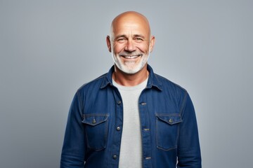 Portrait of a grinning man in his 50s sporting a versatile denim shirt against a white background....