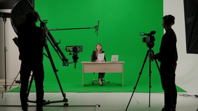News anchor at work, woman journalist presenter telling breaking news, view of a backstage studio TV news shooting, chroma key template.