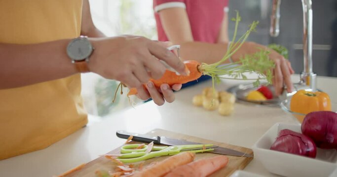Diverse couple preparing and washing fresh vegetables in kitchen, slow motion