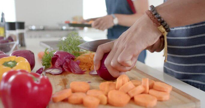 Diverse couple preparing fresh vegetables and cutting in kitchen, slow motion
