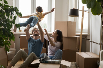 Cheerful young loving family with cute little daughter celebrate moving day, having fun, playing...