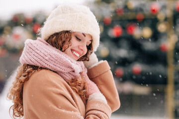 A snowy cityscape with a young woman wearing winter attire, posing in front of the Christmas tree....