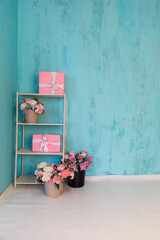 shelf with gifts and flowers on turquoise background interior
