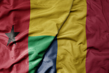 big waving national colorful flag of chad and national flag of guinea bissau .