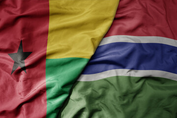 big waving national colorful flag of gambia and national flag of guinea bissau .