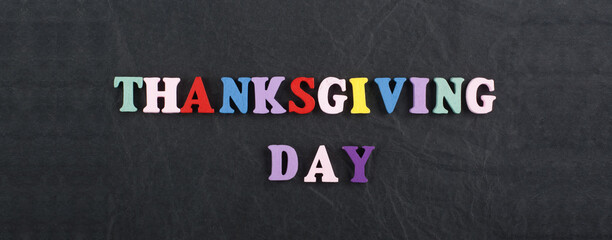 Fototapeta premium THANKSGIVING DAY word on black board background composed from colorful abc alphabet block wooden letters, copy space for ad text. Learning english concept. Banner.