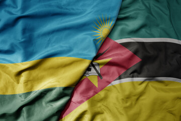 big waving national colorful flag of mozambique and national flag of rwanda .