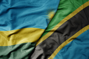 big waving national colorful flag of tanzania and national flag of rwanda .