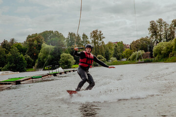 Wakesurfer on a board rides on the waves on the lake